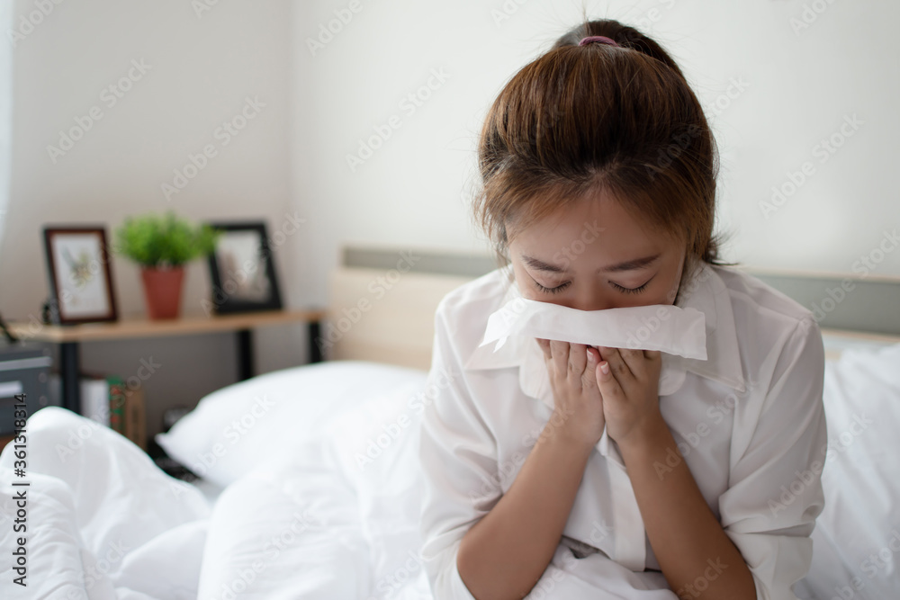 Young business woman is sick and sneezing heavily on the bed. She can't work. Young business woman is sick and sneezing heavily on the bed. She can't work.