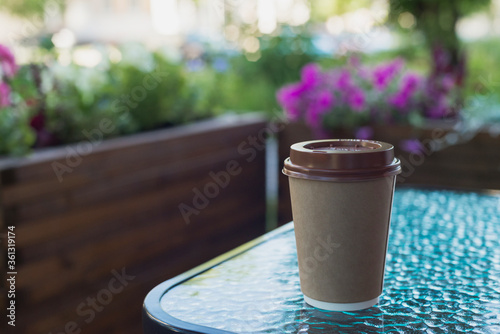 brown paper coffee cup to go on table in street cafe, lifestyle horizontal stock photo image template