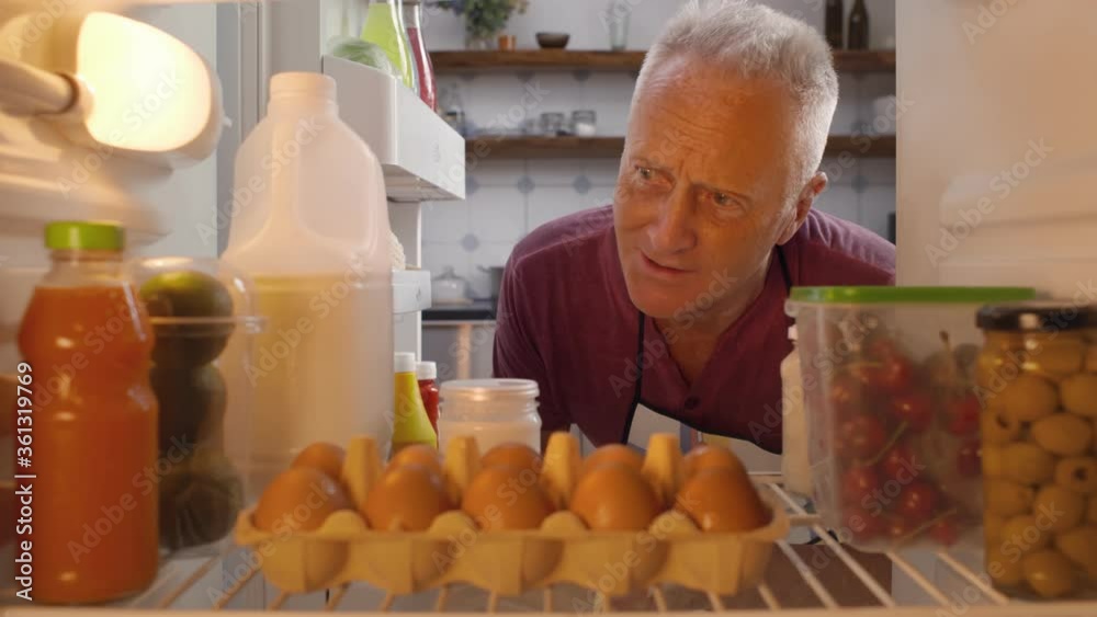 Mature man taking ingredients from fridge for cooking meal Mature man taking ingredients from fridge for cooking meal