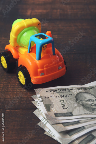Plastic toy cement mixer truck with Indian currency on wooden table - Vehicle loan concept
