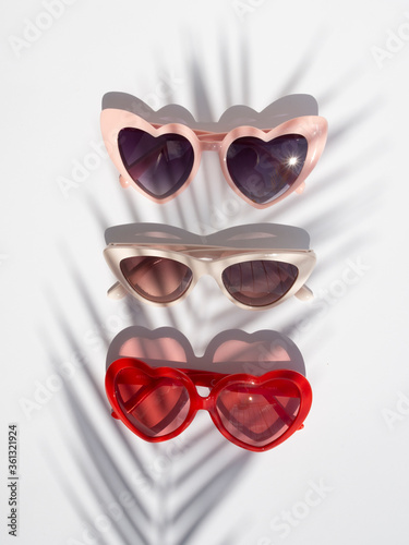 Summer fashion concept. Set of stylish female Sunglasses with palm leaf shadow on a white background