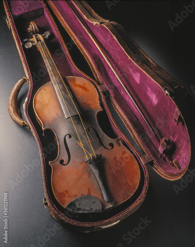 old distressed violin and bow in case with broken strings and dust