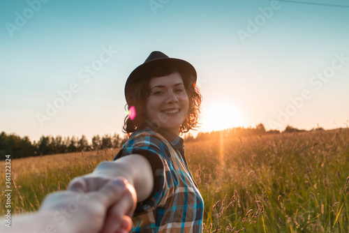 Fototapeta Naklejka Na Ścianę i Meble -  beautiful girl in nature. girl holds the hand at sunset in the field. woman smiling with a hat on nature.