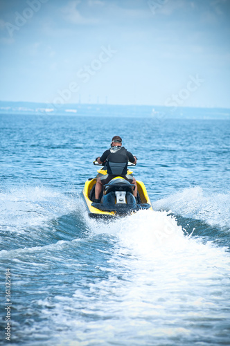 Man of jet ski rider performs on the waves with much splashes goes to sea