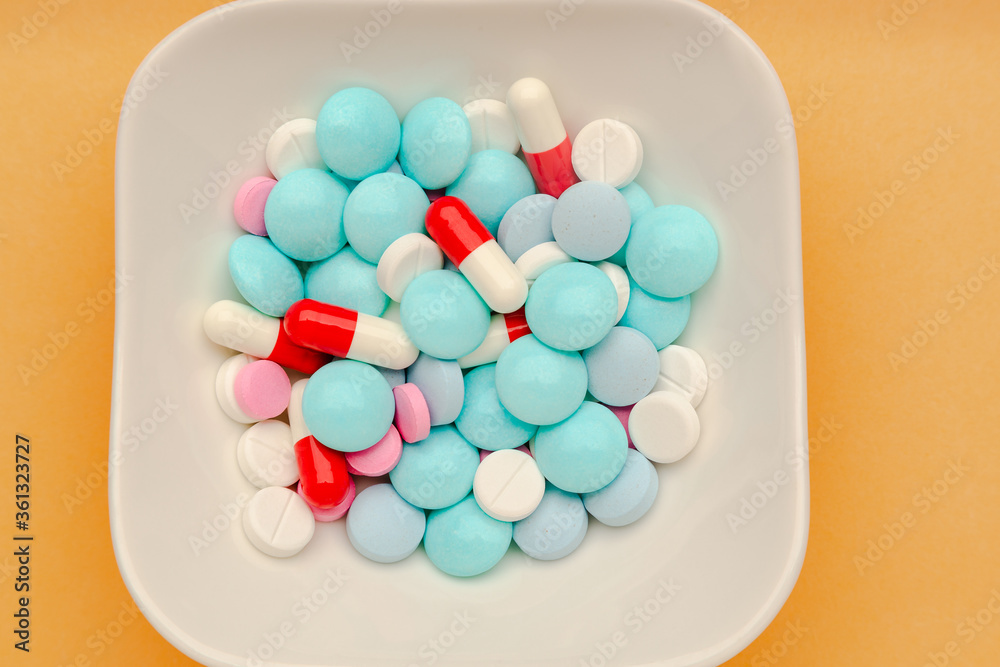 White plate with different pills on it with knife and fork, concept of drugs addiction. White plate with different pills on it with knife and fork, concept of drugs addiction.