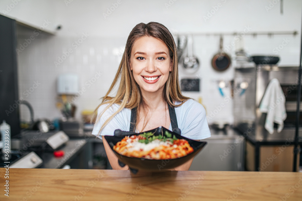 Beautiful young woman serving Italian pasta.
