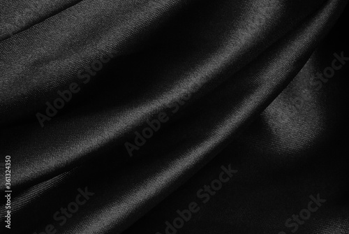 Shiny black folded fabric. Liquid wavy background.