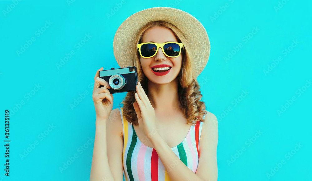 Summer portrait happy smiling young woman with retro camera wearing a summer straw hat on blue background Summer portrait happy smiling young woman with retro camera wearing a summer straw hat on blue background