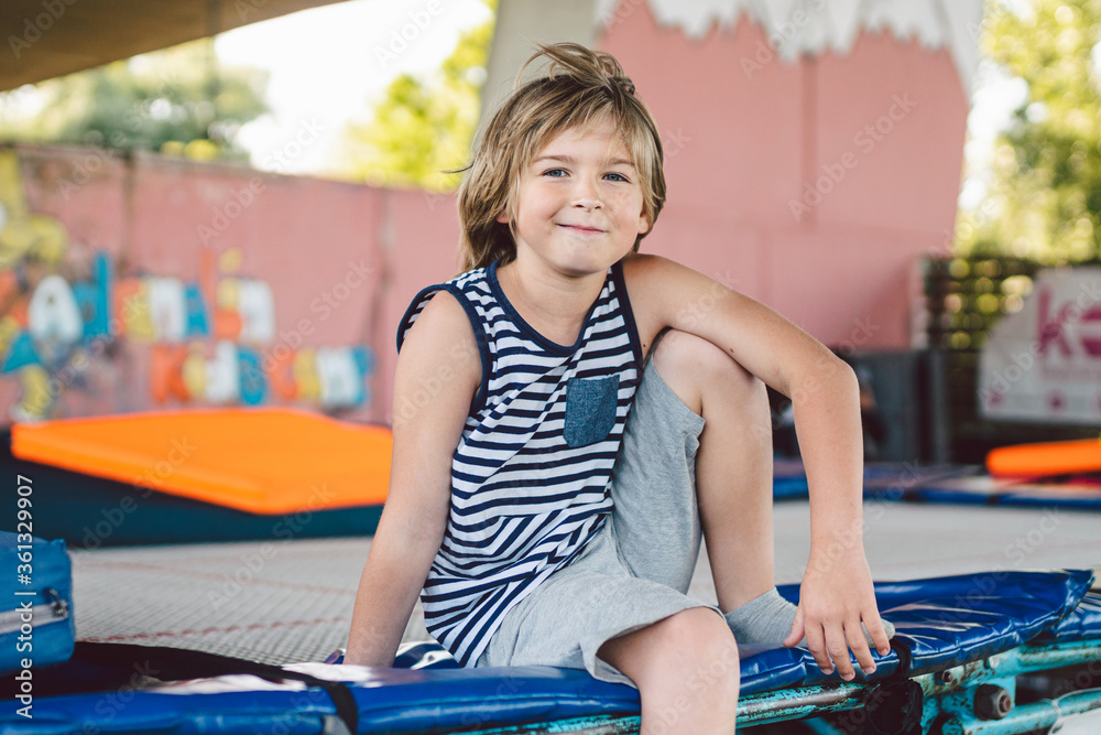 Athlete Caucasian boy sitting on trampoline after training. child is  engaged in trampolining on professional trampoline outside. Little  youngster relaxing from jumping on trampoline. Acrobatic sport Stock Photo  | Adobe Stock