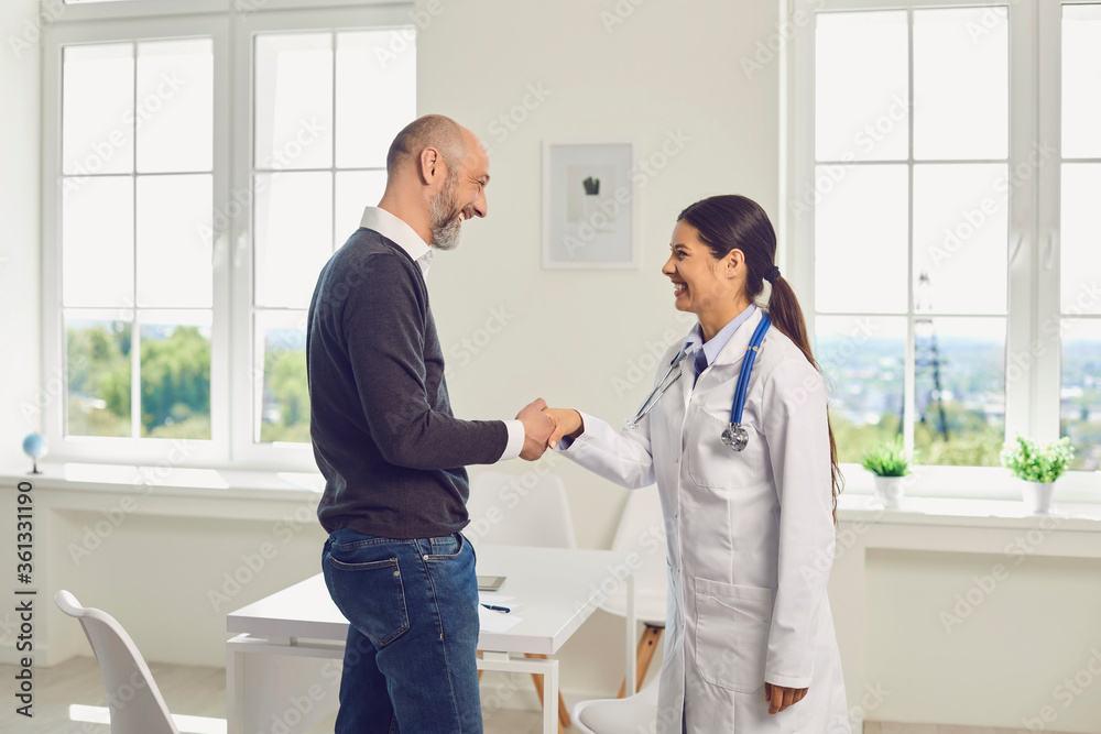 Doctor or nurse woman shaking hands with a patient standing in a hospital clinic. Doctor or nurse woman shaking hands with a patient standing in a hospital clinic.