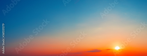 Panorama of dramatic sunset sky with setting sun photo
