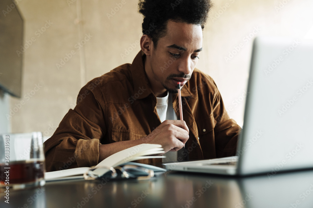 Photo of african american man using laptop while working at table Photo of african american man using laptop while working at table