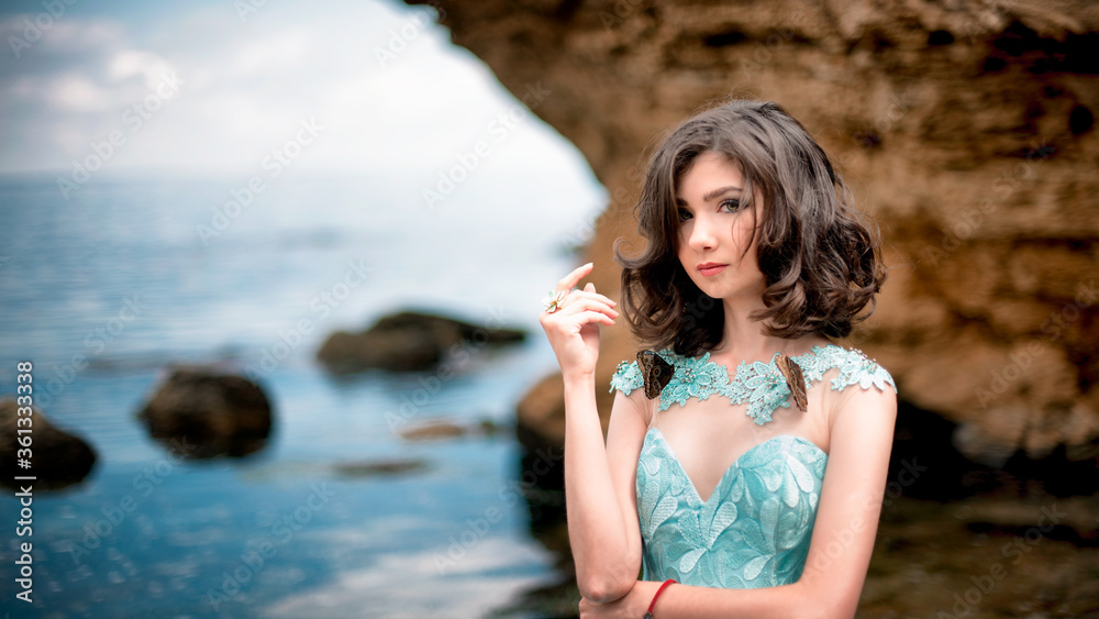 Beautiful young girl in a dress with butterflies on the beach. Portrait