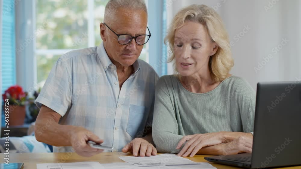Senior couple at home discuss income and pay bills online scanning qr-code Senior couple at home discuss income and pay bills online scanning qr-code