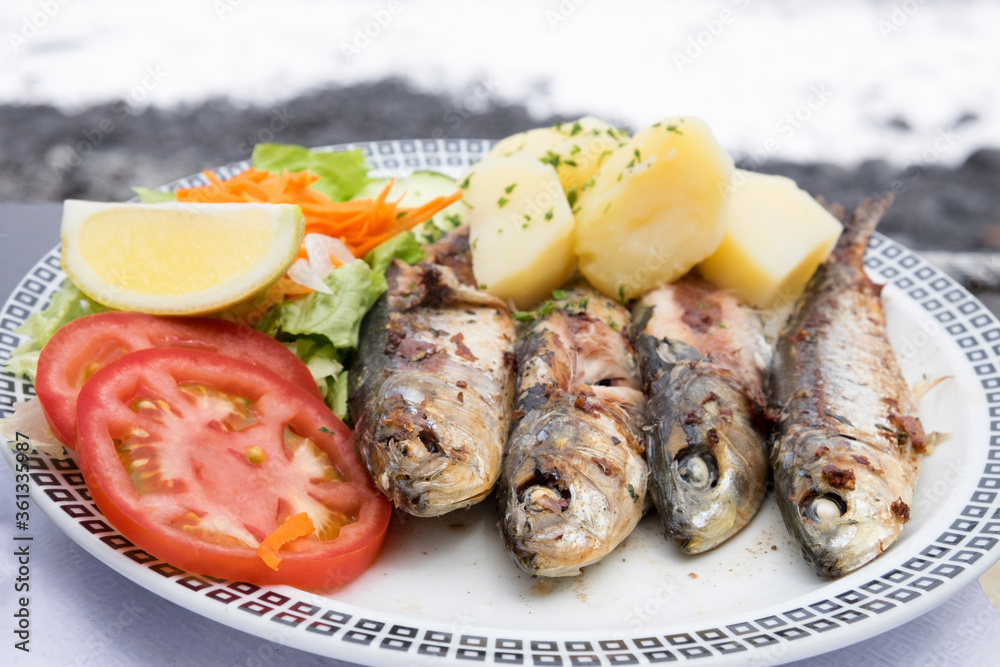 Traditional seafood dish from Madeira island cuisine - oily grilled sardines served with boiled potatoes and fresh vegetables
