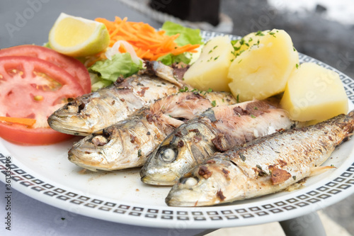 Traditional seafood dish from Madeira island cuisine - oily grilled sardines served with boiled potatoes and fresh vegetables