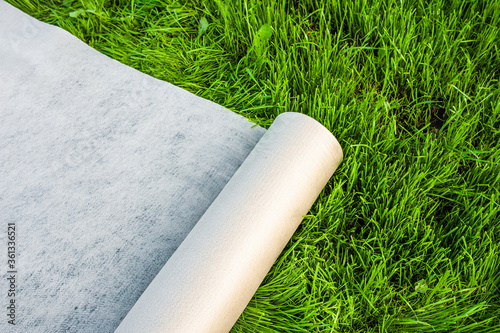 A roll of white geotextile lies on the green grass outside photo
