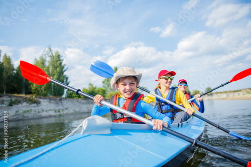 Happy boy kayaking on the river on a sunny day during summer vacation