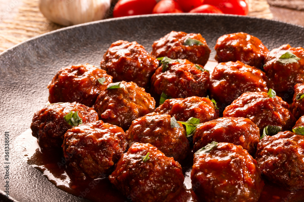 Traditional spicy meatballs in tomato sauce on wooden background. Selective focus.