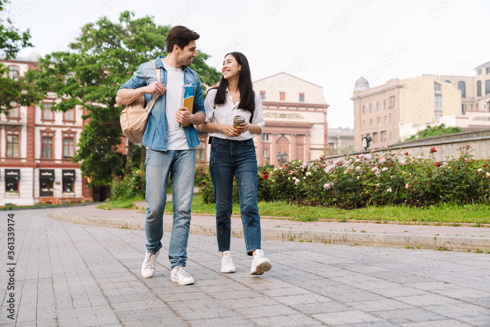 Image of couple talking and drinking coffee takeaway while walking