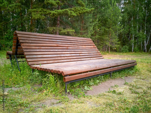 Fototapeta Naklejka Na Ścianę i Meble -  Lying brown bench in a green park in nasty day