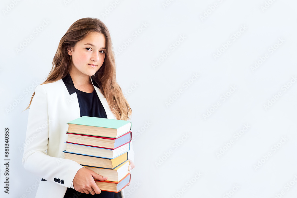 Teenage student girl in white blazer holding in hands pile of books looking at camera over white background Teenage student girl in white blazer holding in hands pile of books looking at camera over white background