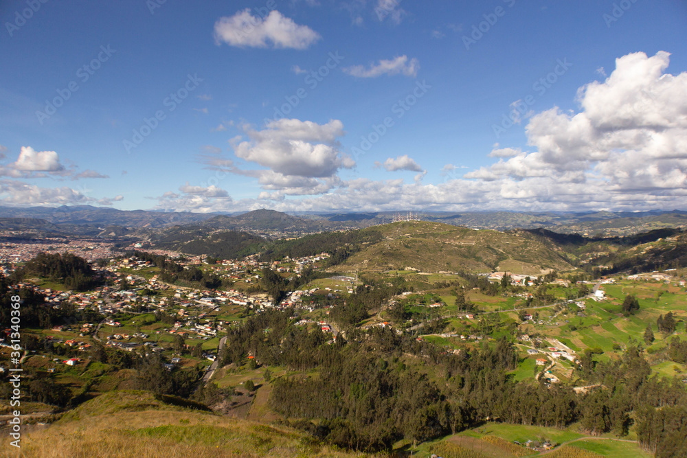 panoramic view of a town between a landscape of forests and mountains on a sunny day with little cloudiness
