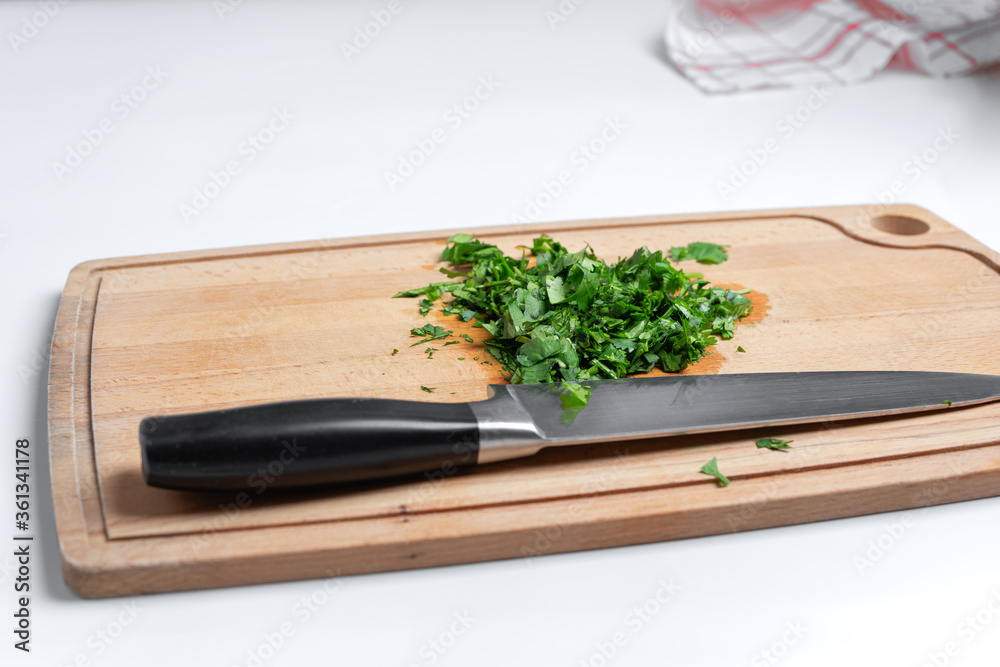 Sliced parsley on a wooden Board next to a knife in the kitchen Sliced parsley on a wooden Board next to a knife in the kitchen