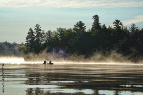 Canoeing at sunrise on a misty lake