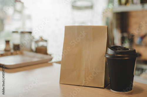 hot black coffee cup and dessert paper bag waiting for customer on counter in modern cafe coffee shop, food delivery, cafe restaurant, takeaway food, small business owner, food and drink concept © Vittaya_25
