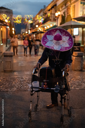 Fototapeta Naklejka Na Ścianę i Meble -  Old singing Charro walking down the street in San Cristobal de las Casas, Mexico