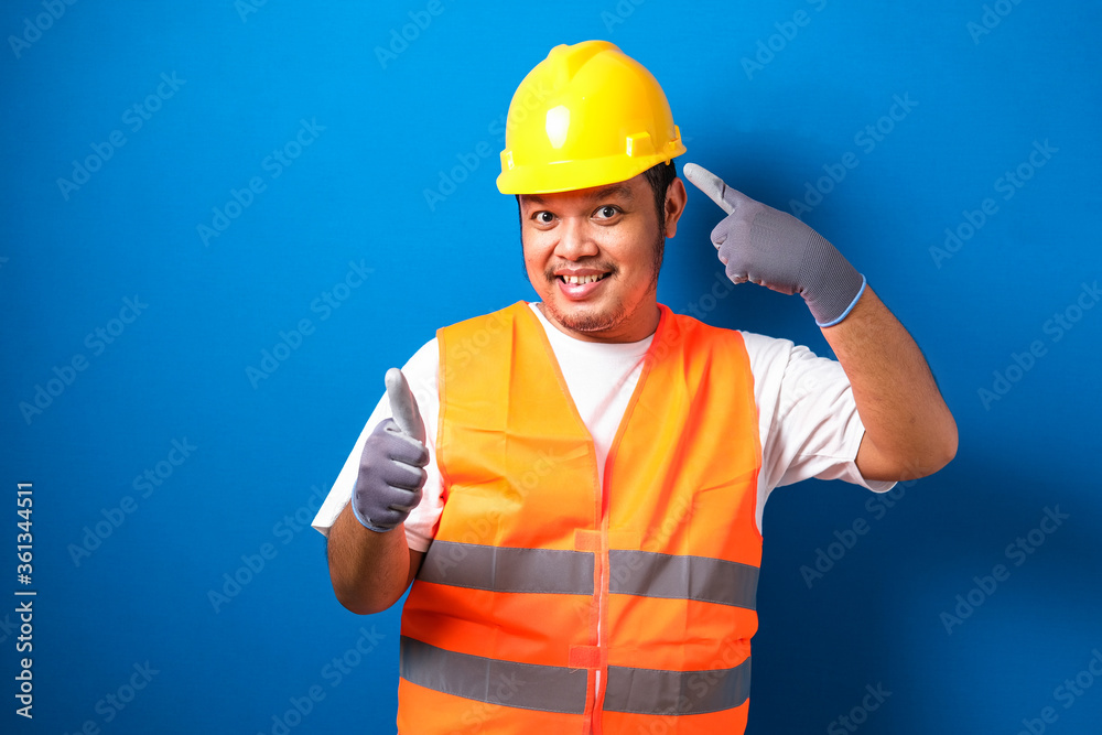 Asian workers wearing helmets are seen looking for ideas in completing work against blue background Asian workers wearing helmets are seen looking for ideas in completing work against blue background
