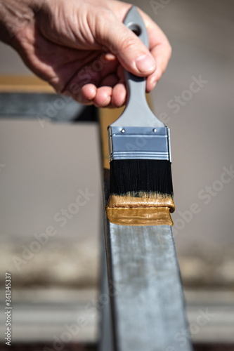 man is painting a metal railing with copper varnish