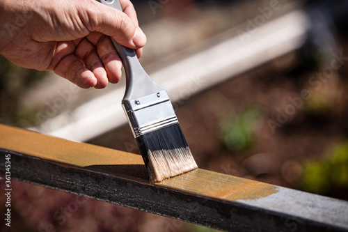 Fototapet man is painting a metal railing with copper varnish