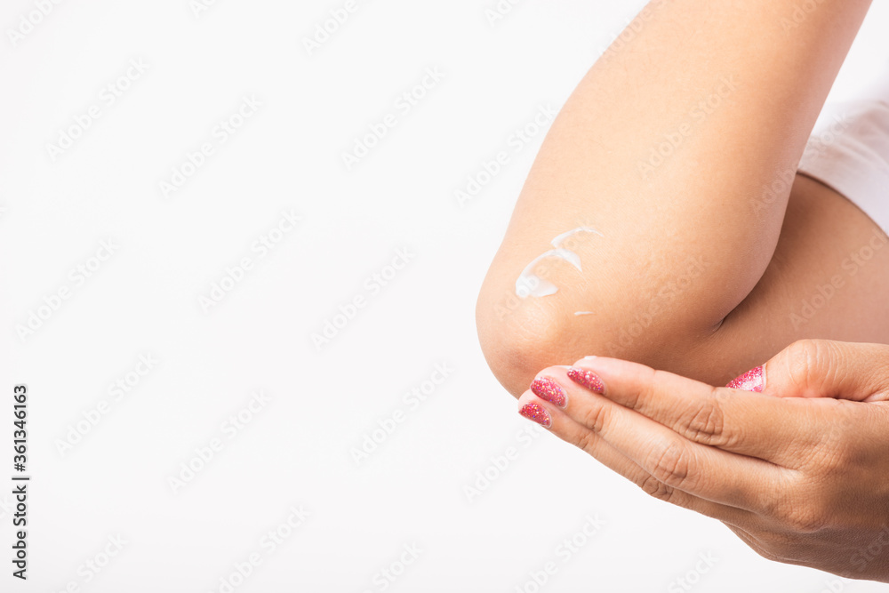 Fototapeta premium Closeup young Asian woman applies lotion cream on her elbow, studio shot isolated on white background, Healthcare medical and hygiene skin body care concept