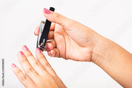 Close up young Asian woman have tool cutting nails fingernails on finger using a nail clipper. Female using tweezers by herself  studio shot isolated on white background  Healthcare concept