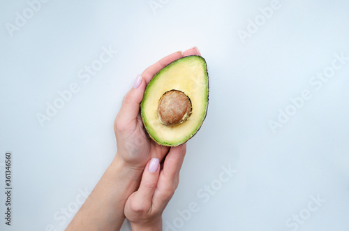 Close up woman's arm with a half of ripe fresh avocado isolated on white