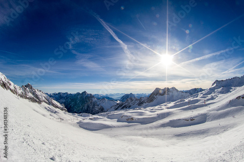 sun on ski slope and panorama of the snowy alps from the ski resort © Lahodyuk