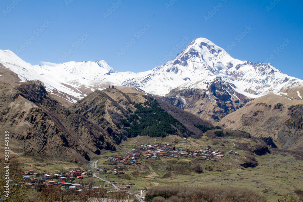 panorama of Kazbek mountain village meadow and snow