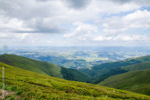 Panorama of green mountains with clouds and village