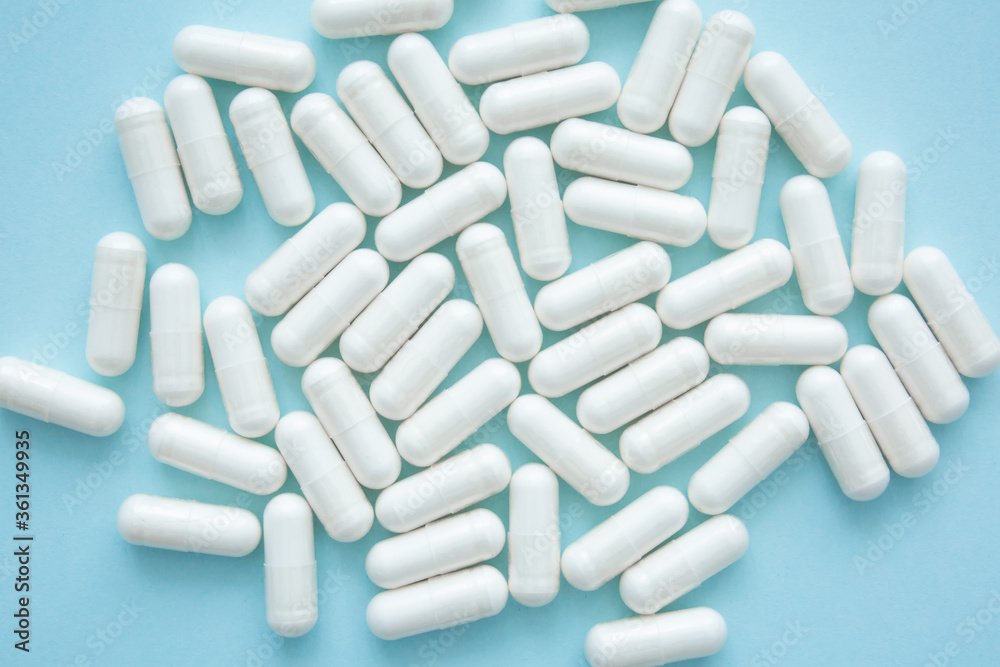 Health concept. White capsules with drug on blue background. Handful of pills, treatment. Health concept. White capsules with drug on blue background. Handful of pills, treatment.