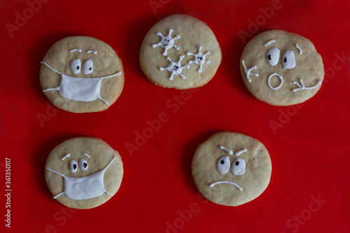 round sugar cookies with painted faces on a red background, the coronavirus virus attacks people without masks, fear, fear, masked cookies