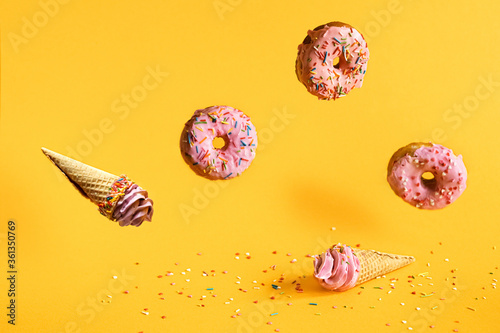 levitation of pink marshmallow waffle cones and donuts on a yellow background. the concept of a children's holiday. selective focus.