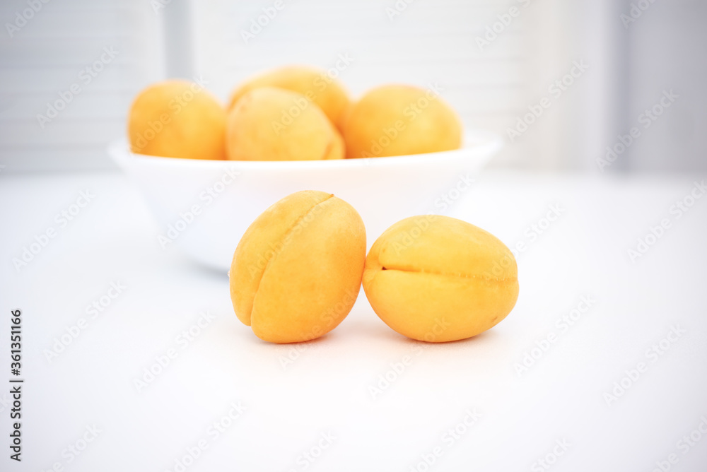 Apricot on a wooden white background. Sliced apricot, apricots in a plate, apricot slices