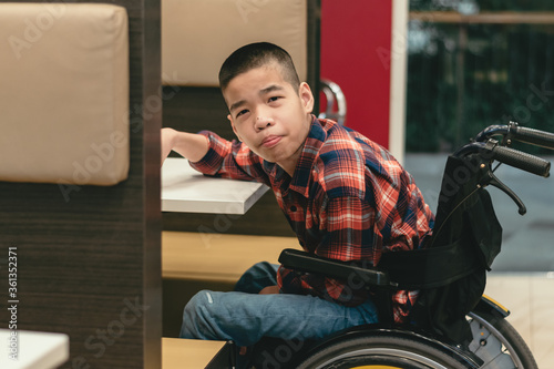 Disabled child on wheelchair waiting to eat food in the cafe, Restaurant background, Special children's lifestyle,Life in the education age of special need children,Happy disability kid concept.