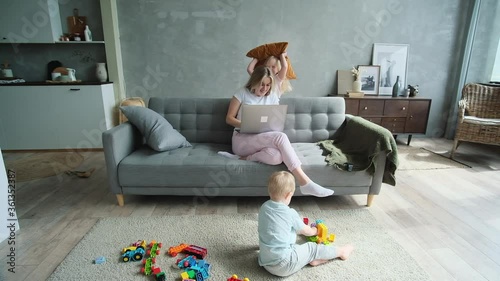 Mother working at home and naughty blond kids playing