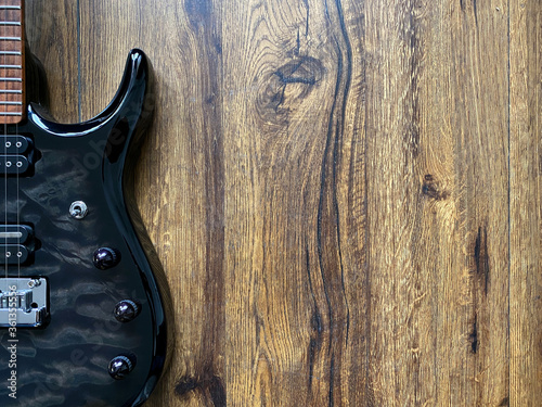 black electric guitar made from quilted maple top Popular musician on veneer brown wood background with copy space on right for letter. business and music concept. Wallpaper or background. top view.