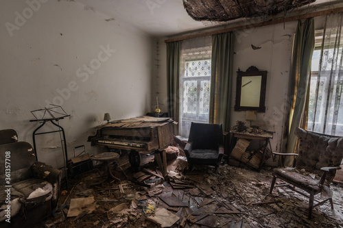 abandoned room with a piano and a armchair