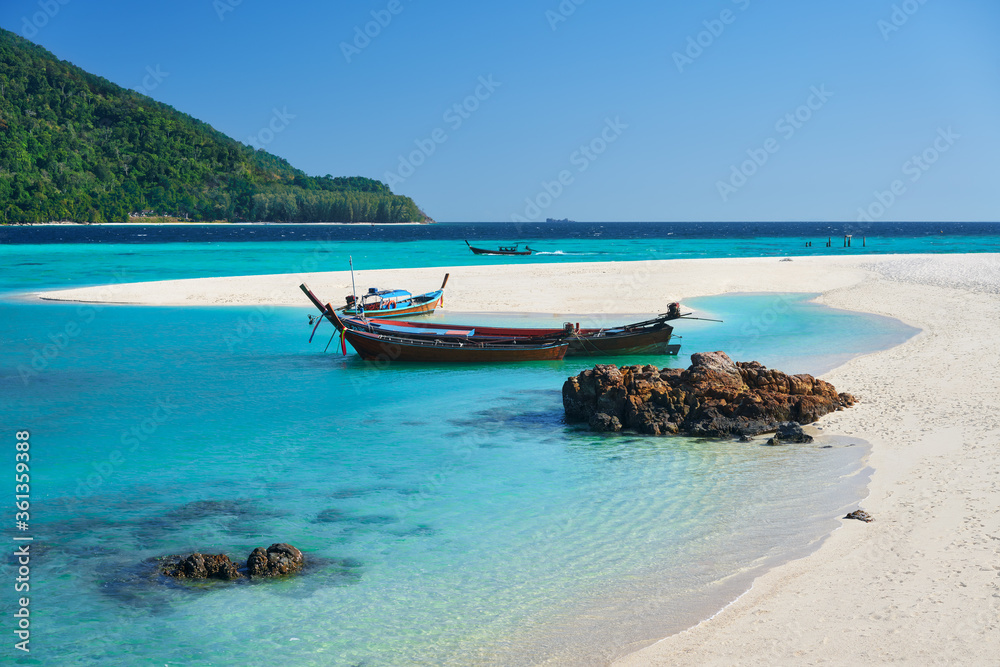 Boat on tropical white sandy beach and turquoise water