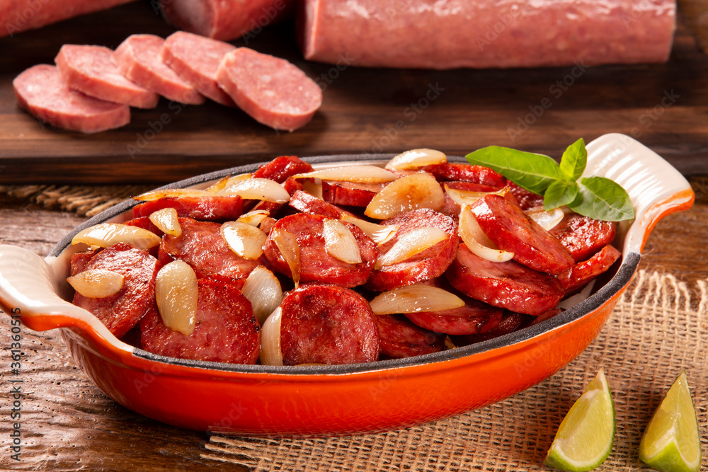Smoked sausage with bread and onions on wood background. Snack appetizer calabrese sausage with onion. Smoked sausage with bread and onions on wood background. Snack appetizer calabrese sausage with onion.